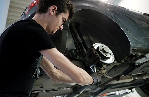 Detailaufnahme von den Händen eines Mechanikers, der gerade etwas am Motor eines Fahrzeuges repariert. 